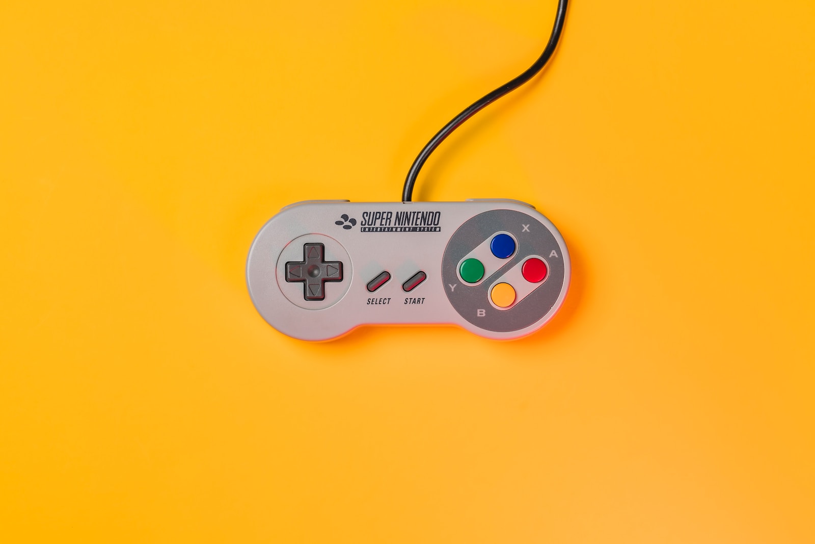 white nintendo game controller on yellow surface